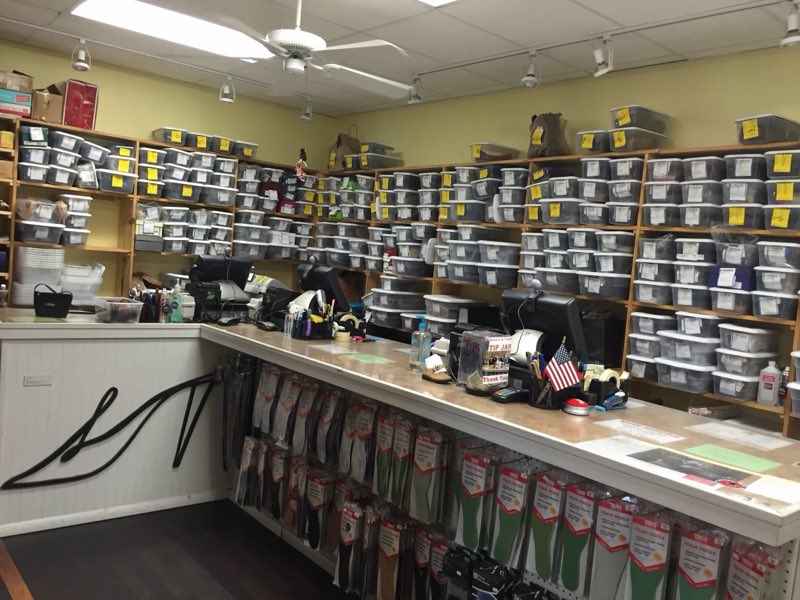Shop interior with a counter and shelves full of labeled bins of finished repair orders.